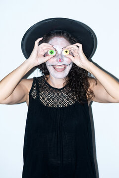 Woman in Halloween makeup holding gummy eyeball candies