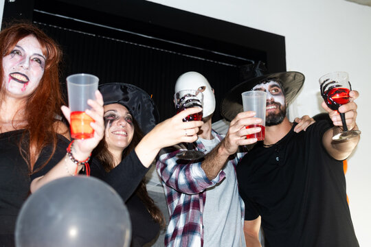 Friends raising drinks at Halloween costume party