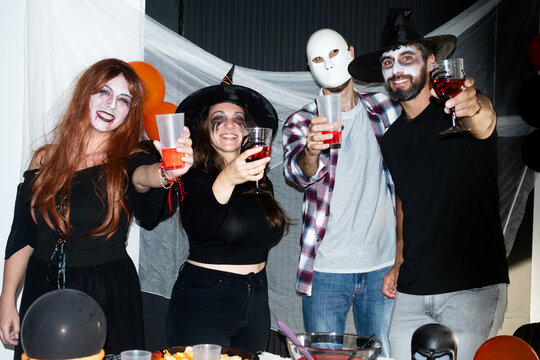 Friends raising drinks at Halloween costume party