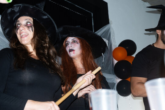 Friends in witch costumes having fun at Halloween party