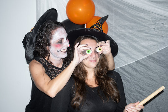Women playing with gummy eyeball candies at Halloween celebration