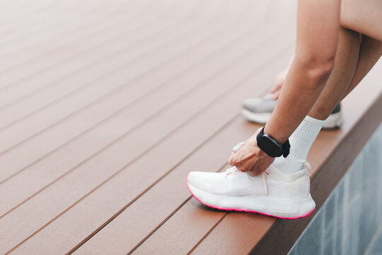 Cropped shot of runner tying white sneaker laces before outdoor workout
