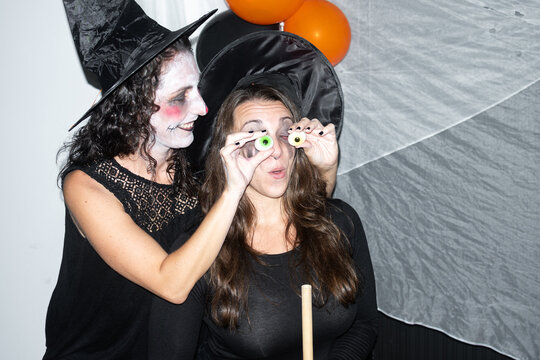 Women playing with gummy eyeball candies at Halloween celebration