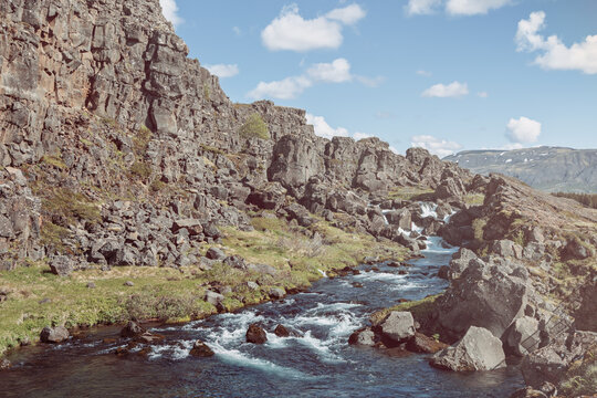 Oxara current bends through a narrow gorge in Thingvellir National Park, Iceland. Nostalgic analog film processing gives the water softened cyan, faded warm rock tones, and subdued contrast.