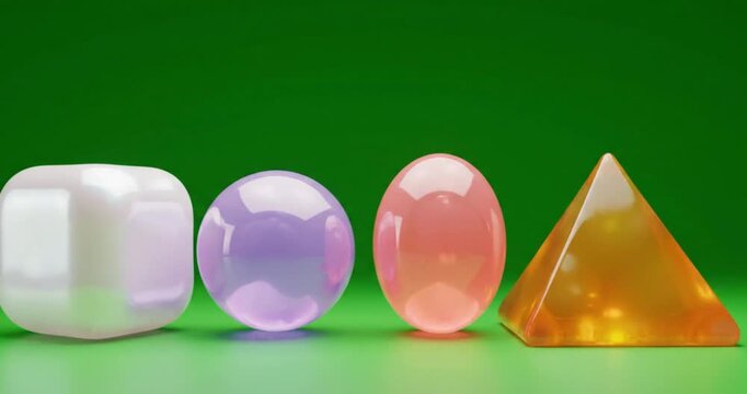 3D glossy translucent geometric shapes cube sphere oval and pyramid on green screen background