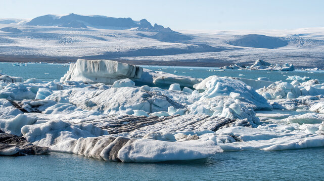 A beautiful icebergs breaking from Vatnajokull glacier and drifting across Jokulsarlon lagoon, Iceland, reflecting glacier melt and global warming in a striking summer landscape.