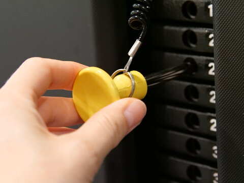Hand Adjusting Resistance Level with Yellow Pin on Weight Stack Machine in Fitness Club
