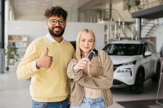 Diverse couple celebrating new car ownership at dealership