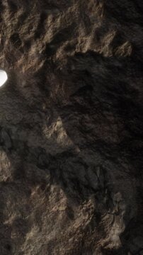A bright light shines on rocky terrain, highlighting the texture and details of the surface. This scene occurs in a remote area, showing the contrast of shadows and light.