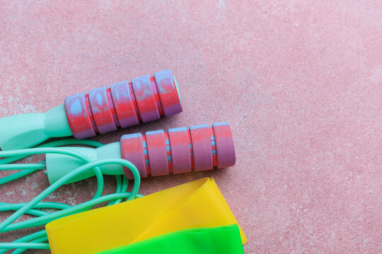 equipment jump rope and sports fitness rubber bands used for exercise on a pink surface during workout session