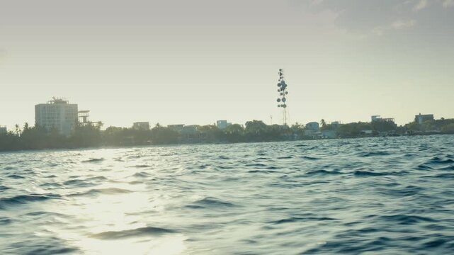 Contre Jour Backlit View of Ukulhas Island Silhouette with Bright Sun Reflections on Ocean Waves from Boat in Maldives