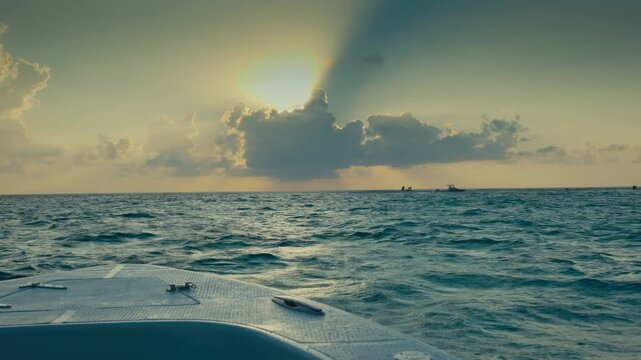 POV Shot from Front Bow of Speedboat Sailing Towards Ocean Horizon with Dramatic Sunbeams at Sunset in Maldives