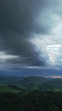 Vertical Aerial View of Dark Storm Clouds Over Hilly Mountain Landscape