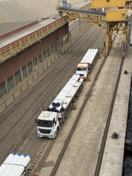 seaport wharf heavy trucks deliver big diameter pipes.