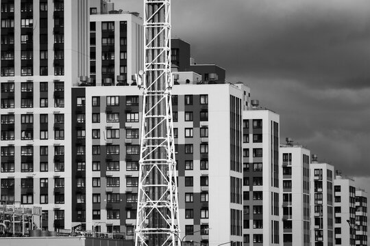 Monochrome view of high rise apartment buildings and construction tower, moody cloudy sky, urban density and architectural pattern.
