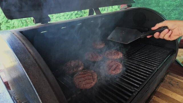 Man Checks Doneness of Burgers on Grill in Slow Motion Today