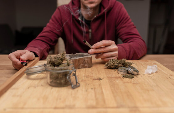 lose up of man sitting at table while smoking cannabis