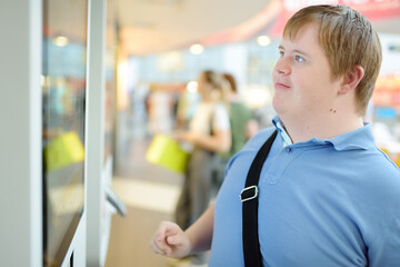Portrait of a teenager with Down syndrome in a big city. Boy with Down syndrome chooses food on...