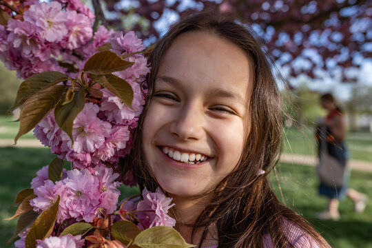 Smiling girl enjoys spring blossoms outdoors
