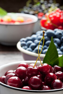 Bowl of sour cherries and bowls of different berries in the background