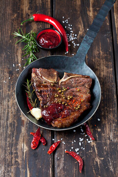 Porterhouse steak with spices and tomato sauce in frying pan