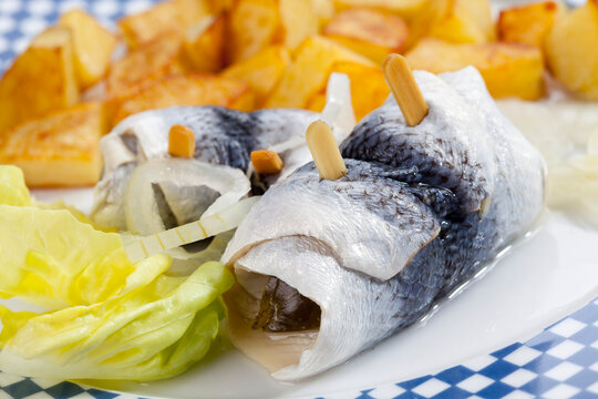 Rollmop herring with roasted potatoes and onions on a plate