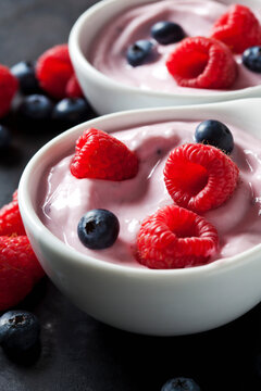 Two bowls of fruit yoghurt with blueberries and raspberries