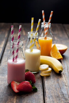 Row of three bottles with different fruit smoothies and orange juice
