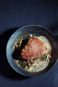 Fried fillet of beef with herb butter, peppercorns and rosemary in a pan