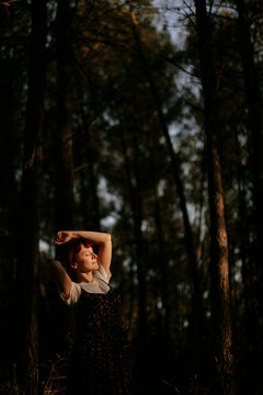 Relaxed woman enjoys sunlight in a dark woodland environment