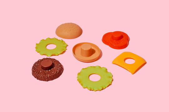 Deconstructed plastic toy hamburger ingredients on pink background