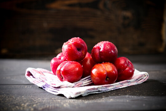 Pile of Chinese plums (Prunus salicina) on kitchen towel and dark wooden table
