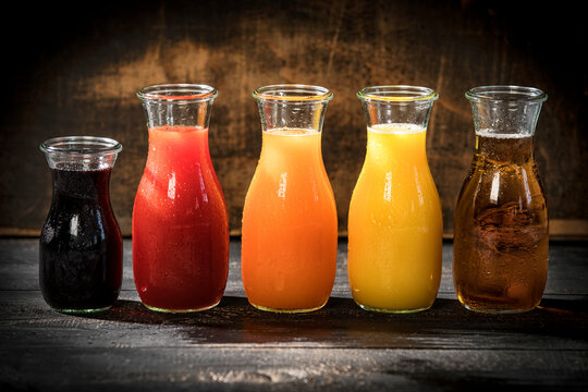 Row of five glass bottles of various fruit juices