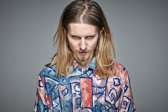 Portrait of starring young man with long blond hair and beard