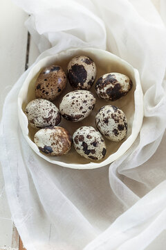 Bowl of quail eggs on white cloth and wood