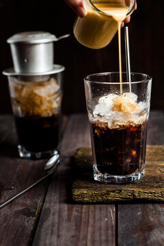 Pouring sweetened condensed milk over vietnamese iced coffee