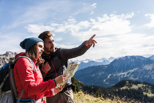 Austria, Tyrol, young couple with map in mountainscape looking around