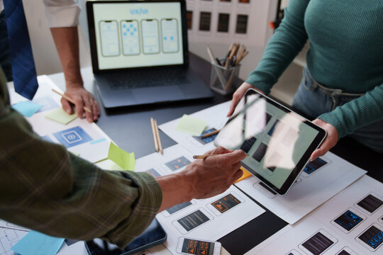 UX and UI designers collaborating on mobile application development, brainstorming user experience concepts and creating interface wireframes for new digital projects