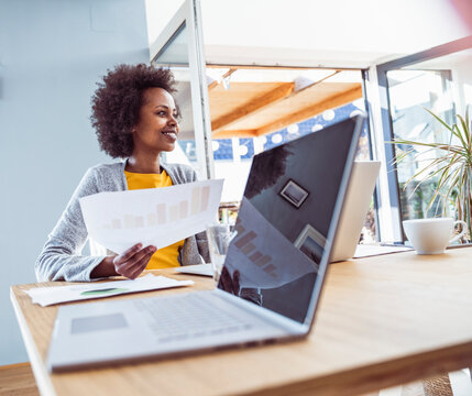 Smiling woman analyzes business document at her home office desk