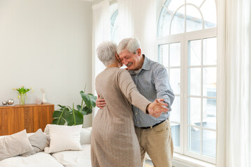 Fototapeta premium Keep moving. Romantic senior mature couple dancing to music together at home. Happy smiling family retired man woman husband wife having fun enjoying time together. Family moment love care