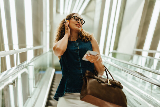 Woman sings with headphones on escalator during city commute