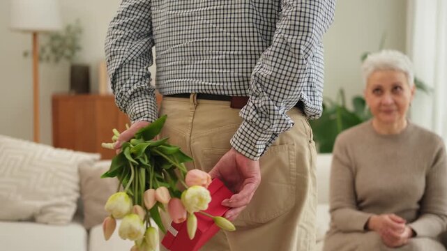 Senior man giving flowers gift box to old woman. Happy family couple. Husband wife with present tulip flowers bouquet celebrating women day birthday family wedding date Valentines day. In love people