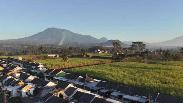 Aerial View of Residential Houses and Sugarcane Fields with Mountain Backdrop at Morning