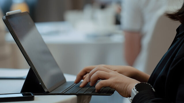 Close up a person hand typing on a tablet with an external keyboard in meeting room at office