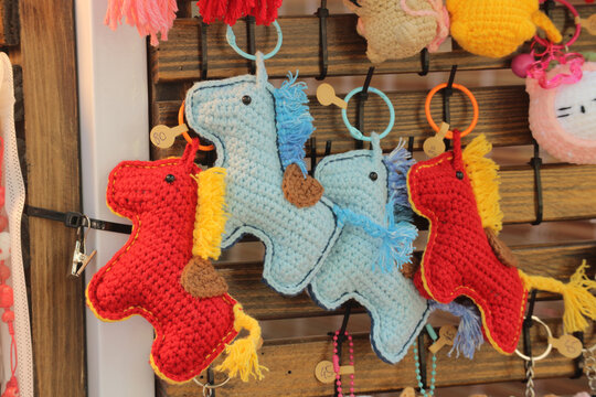 Handmade crochet horse keychain on wooden display market shelf, knitted amigurumi horse toys craft souvenir for sale, Vietnam