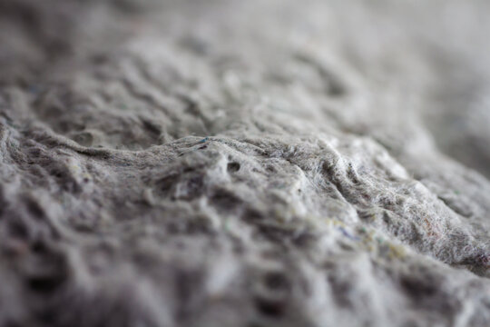 Extreme close up of old gray handmade paper clay with a structure and rough texture. Paper recycling. Selective soft focus, shallow depth of field.