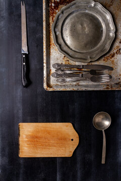 Old various kitchen utensils on black chalkboard background. Food themed flat lay.