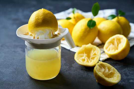 Fresh lemon juice in bowl and ripe lemons on dark table, selective focus. freshly squeezed lemon juice .