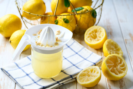 Fresh lemon juice in bowl and ripe lemons on white table, selective focus. freshly squeezed lemon juice .