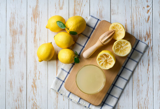 Making lemon juice from ripe lemons. Freshly squeezed lemon juice on a white table, top view.